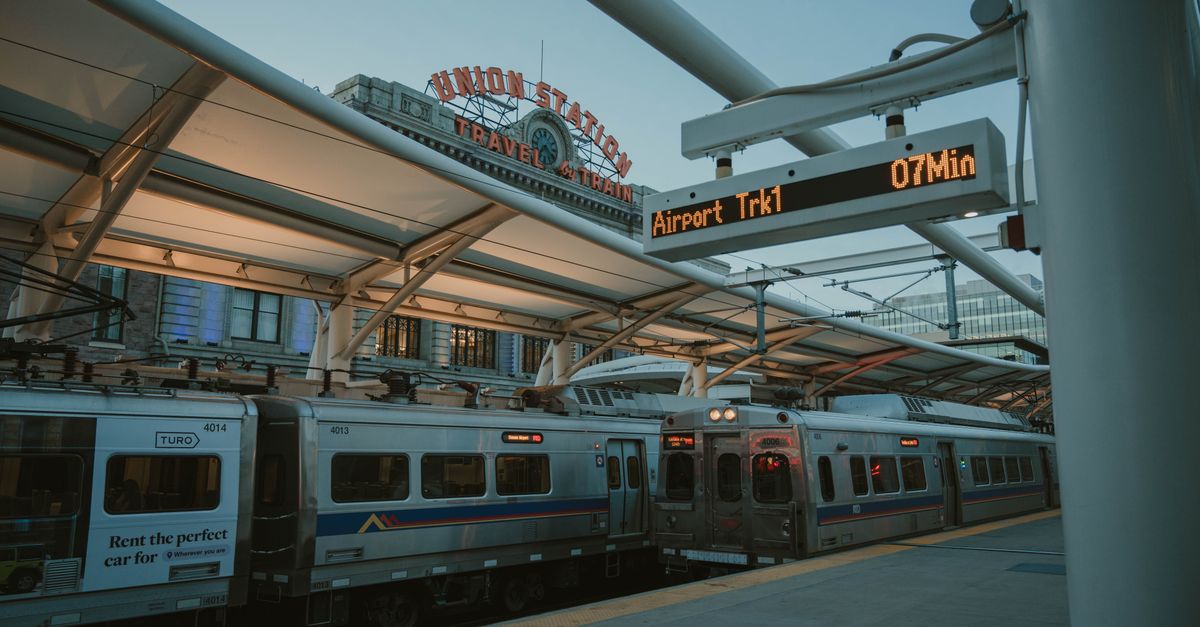 Evening train at Denver Union Station with iconic sign and transit information display.